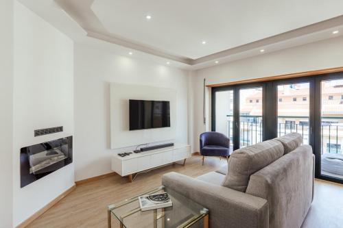 a living room with a couch and a tv at Glam 2 bedroom In Massamá in Massamá