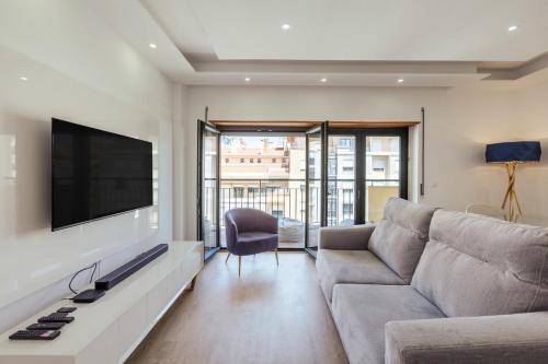 a living room with a couch and a flat screen tv at Glam 2 bedroom In Massamá in Massamá