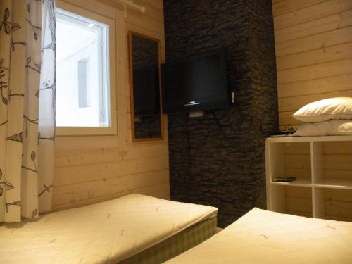 a room with a bed and a television on a wall at Villa Korpilo in Somero