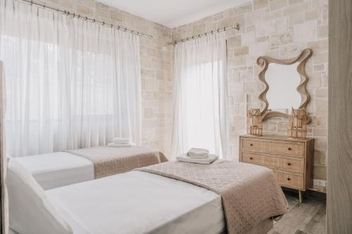 two beds in a bedroom with a mirror and a dresser at Guince House by All About Paxos in Oziás