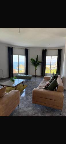 a living room with couches and a table and windows at Villa Belle-Vue in Tabarka