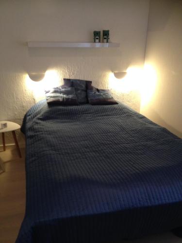Un dormitorio con una cama azul con dos luces. en Sommerlyst en Løkken