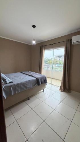 a bedroom with a bed and a large window at Apartamento Ilhéus próximo à praia in Ilhéus
