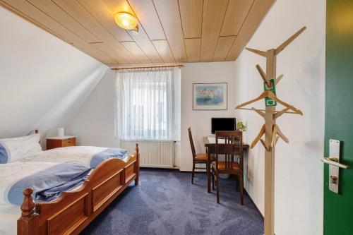 a bedroom with a bed and a desk and a table at Hotel Garni Siedlerstube 2 in Nürtingen