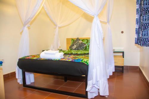 a bedroom with a canopy bed with white curtains at Coffee Pot Hotel in Kisoro