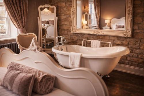 a bathroom with a tub and a sink and a mirror at The Sun Hotel in Warkworth