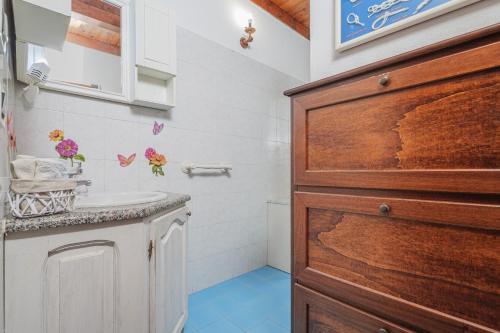a bathroom with a white sink and a wooden door at Villa Montalmutu con vista mare in Nuragheddu