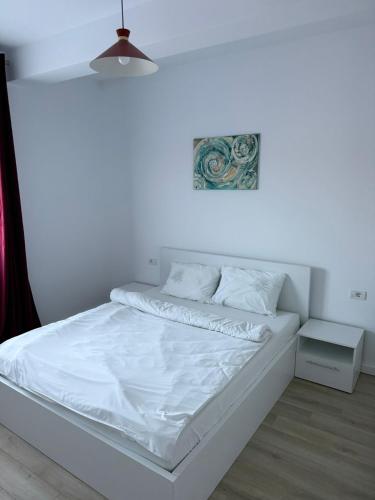 a white bed in a room with a white wall at VISAJ Escape in Timişoara