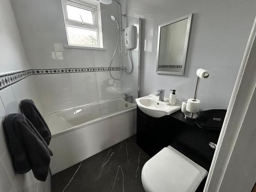 a bathroom with a sink and a toilet and a tub at Bungalow in Mumbles in The Mumbles