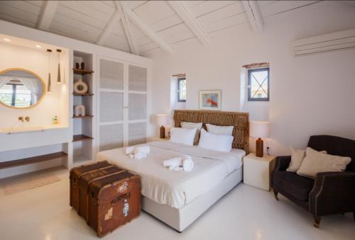 a white bedroom with a bed and a chair at Villa Aeolus Stylish Villa with Pool Masterbedroom with seperate Mezzanine in Koríthion