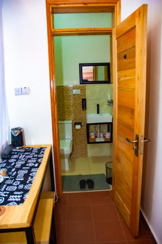 a bathroom with a sink and a toilet and a door at Coffee Pot Hotel in Kisoro