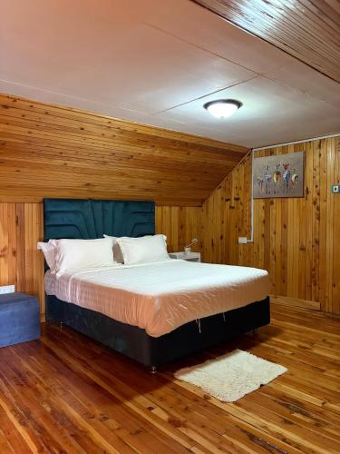 a bedroom with a bed with wooden walls and wooden floors at Kendi Stays - Rustic Penthouse Attic in Eldoret