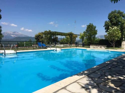 a large blue swimming pool with mountains in the background at Guesthouse Anthoula in Derviziana