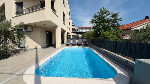 a swimming pool in front of a house at Moonlight Luxury Apartment with Private Pool and Parking in Kaštela