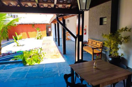 a patio with a wooden table and a table and chairs at VELINN Pousada Entre Praias Itaguá in Ubatuba