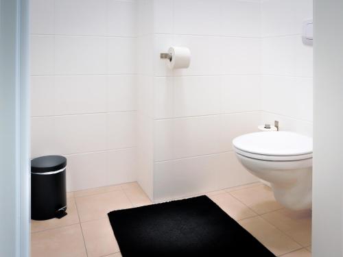 a white bathroom with a toilet and a black rug at SKY9 Penthouse Apartments in Vienna