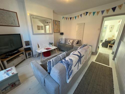 a living room with a couch and a tv at 'Pavilion Cottage' next to Gorleston beach with sea views - pet friendly! in Gorleston-on-Sea