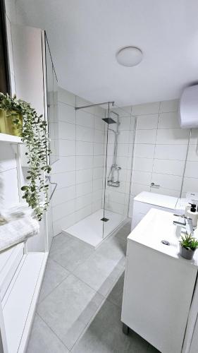 a white bathroom with a shower and a sink at ELKO Apartman in Mogán