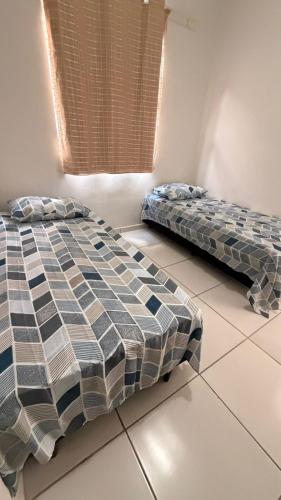 two beds sitting on a tiled floor in a room at Casa jatobá in Petrolina
