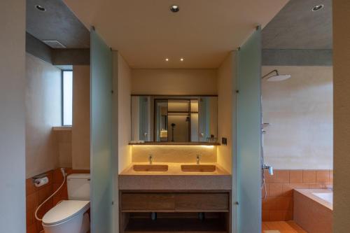 a bathroom with a sink and a toilet and a mirror at The Charm Hotel Phan Thiet in Ấp Bình Hưng