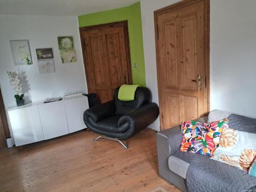 a living room with a black chair and a couch at le gite d'Eliane in Masevaux