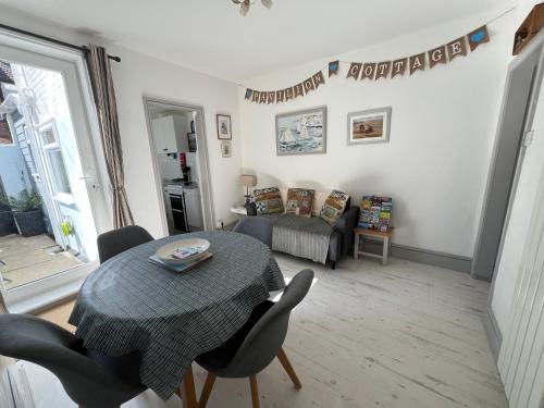a living room with a table and a bed at 'Pavilion Cottage' next to Gorleston beach with sea views - pet friendly! in Gorleston-on-Sea