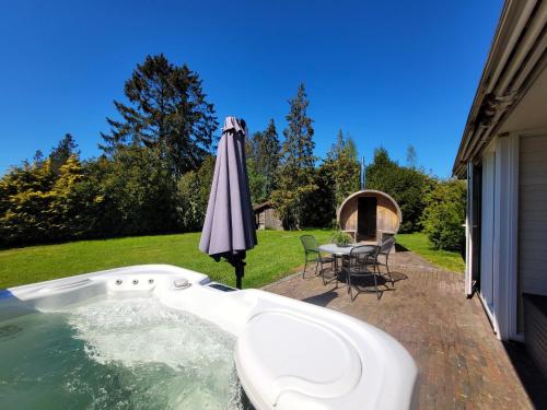 an outdoor hot tub with an umbrella and a table with chairs at Secret Wellness Lonneker in Enschede