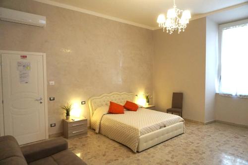 a bedroom with a bed and a couch and a chandelier at Residence Stendhal Guest House in Civitavecchia