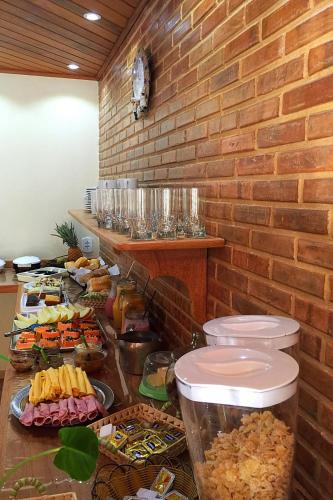 a buffet with food on a counter with a brick wall at Pousada Recanto das Águas in Lumiar