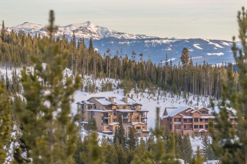 a resort in the snow with mountains in the background at Mountain Lake Condo - Unit 102B in Big Sky