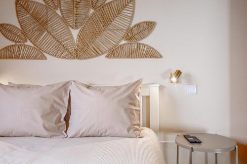 a bedroom with a white bed with a large leaf painting on the wall at Endless Horizon BY YOUR KEY MADEIRA in Santa Cruz