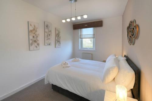 a bedroom with a bed with white sheets and a window at Goldie Apartment 2BR flat in Dalry