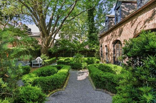 a garden with green bushes and a brick building at Gibbon House at Casa Zoe in Charleston