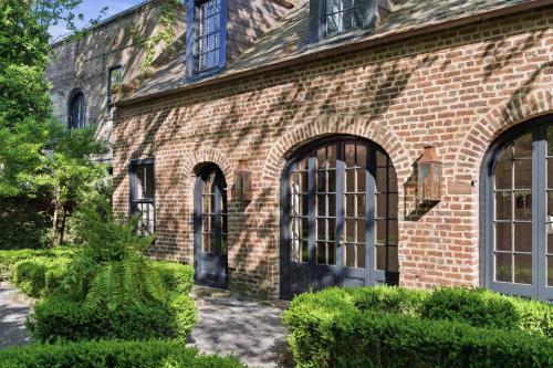 a brick building with large windows and bushes at Gibbon House at Casa Zoe in Charleston