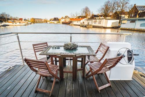 a table and chairs on a boat on the water at Rode Houseboat Zwartsluis in Zwartsluis
