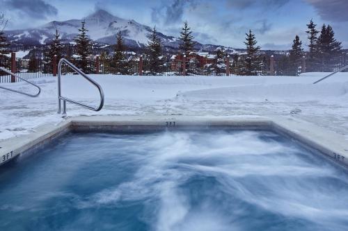 a hot tub covered in snow with a mountain at Mountain Lake Condo - Unit 401B in Big Sky
