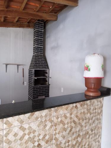 a brick fireplace in a kitchen with a vase on a counter at Recanto Jatobá - Delfinópolis in Delfinópolis