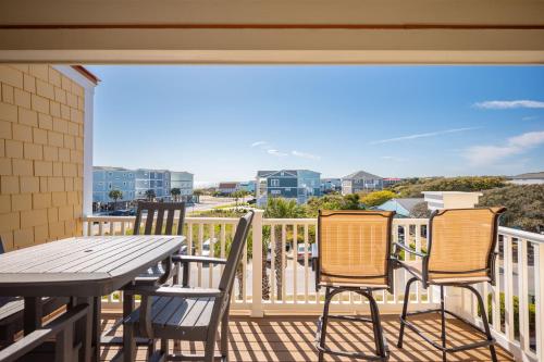 a patio with a table and chairs on a balcony at Sea Tales by Oak Island Accommodations in Oak Island
