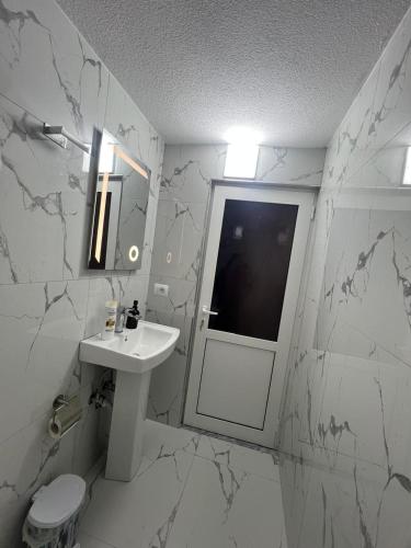 a white bathroom with a sink and a mirror at Dejani Guest House in Pogradec