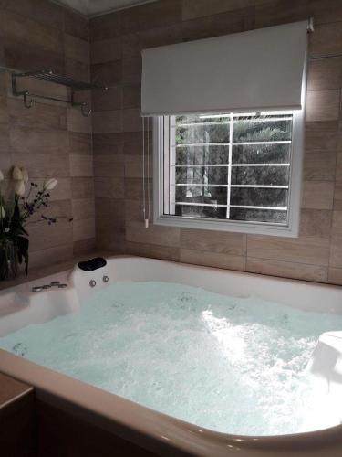 a large bath tub with a window in a bathroom at Refugio de Luna Termal in Termas de Río Hondo