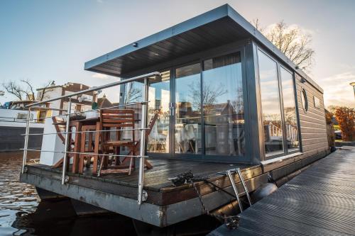 a small house on a boat on the water at The Grey Pearl Houseboat in Zwartsluis