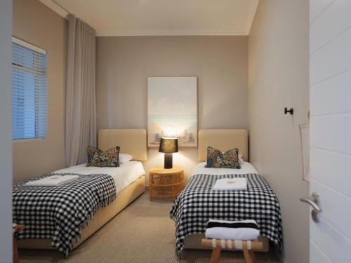 a bedroom with two beds and a lamp in it at Alwil Apartment 11 in Struisbaai