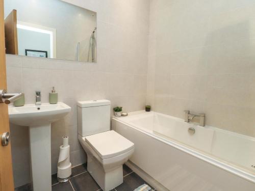 a white bathroom with a toilet and a sink at Flat 2, Dorstan in Carnforth