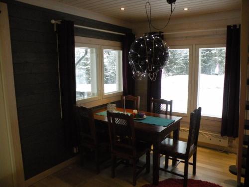 a dining room with a table and chairs and windows at Villa Korpilo in Somero