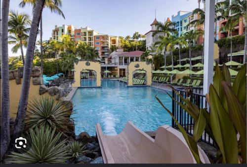 a pool at a resort with palm trees and buildings at Saint Thomas Villa with Ocean view in Frenchmans Reef Heliport