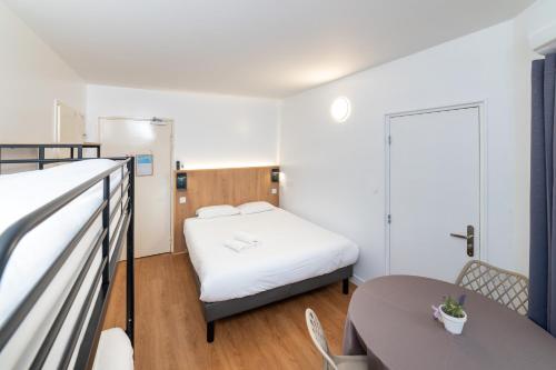 a small room with a bed and a table at Kyriad Direct Macon Sud in Crêches-sur-Saône