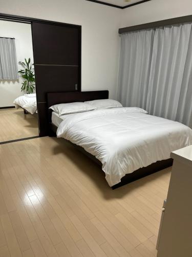 a bedroom with a large bed with a black headboard at Hanako-Home in Fukuoka