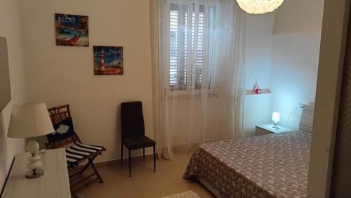 a bedroom with a bed and a chair and a window at Perla di mare in La Maddalena