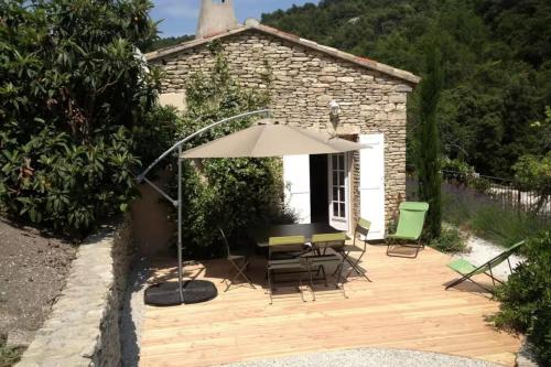 a wooden deck with a table and an umbrella at Maison des Cigales a heavenly setting in Saumane-de-Vaucluse