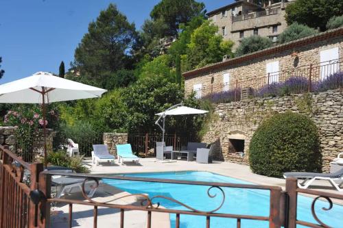 a pool with chairs and umbrellas next to a building at Maison des Cigales a heavenly setting in Saumane-de-Vaucluse